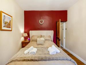 a bedroom with a bed and a red wall at Mill Cottage in Clitheroe