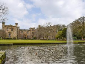 a pond in front of a castle with ducks in it at Mill Cottage in Clitheroe