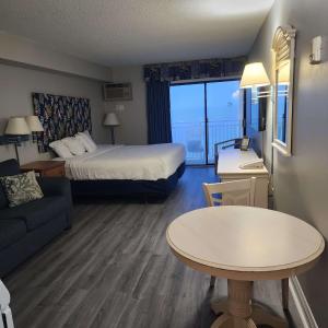 Habitación de hotel con cama, sofá y mesa en Oceanfront Efficiency T902, en Myrtle Beach
