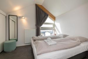 Schlafzimmer mit einem großen weißen Bett und einem Fenster in der Unterkunft Strandvilla 30 Renesse in Renesse
