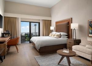 サンアントニオにあるPlaza San Antonio Hotel & Spa, Autograph Collectionのベッド、デスク、ソファが備わるホテルルームです。