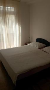 a bedroom with a large white bed and a window at Apartments Topolo Dubrovnik in Dubrovnik