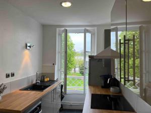 a kitchen with a sink and a large window at Le Logis Cantilien in Lamorlaye