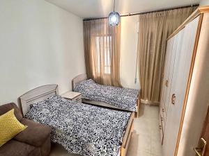 a small room with two beds and a couch at 4 Bedroom Flat in Madaba with AC in Madaba