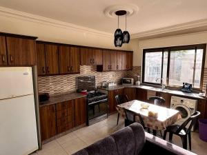 een keuken met houten kasten en een tafel met een eetkamer bij 4 Bedroom Flat in Madaba with AC in Madaba