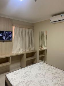 een kleine slaapkamer met een bed en een televisie bij Piazza diRoma com acesso ao Acqua Park e Splash in Caldas Novas