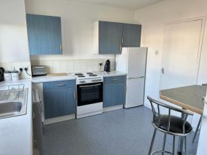 a kitchen with blue cabinets and white appliances at Nithsdale Hotel in Sanquhar