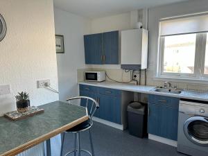 a small kitchen with blue cabinets and a sink at Nithsdale Hotel in Sanquhar