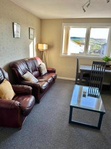 a living room with a leather couch and a table at Nithsdale Hotel in Sanquhar