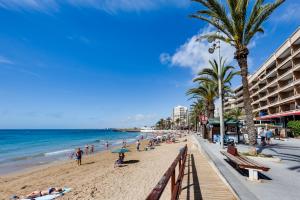 people on a beach with palm trees and the ocean at Penthouse CORBETA SUN in Torrevieja