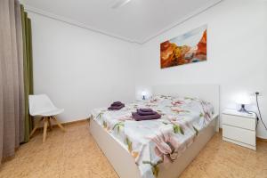 ein weißes Schlafzimmer mit einem Bett und einem weißen Stuhl in der Unterkunft Penthouse CORBETA SUN in Torrevieja