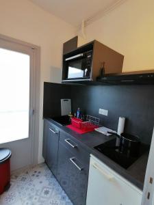 a kitchen with a black counter top with a microwave at Studio Soleil Vernet in Vernet-les-Bains