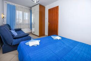 um quarto com uma cama azul e uma cadeira em Apartments Sopic em Rogoznica