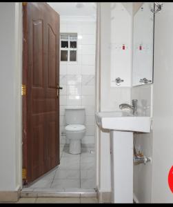 a bathroom with a toilet and a sink and a door at B’s homely in Ruiru
