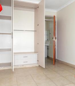 una habitación vacía con estanterías blancas y una cocina en B’s homely en Ruiru