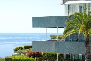 un edificio con una palmera frente al océano en Sea Breeze Retreat, en Cap d'Ail