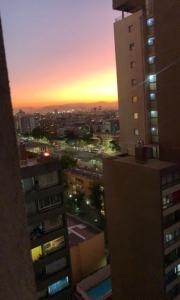 - une vue sur la ville au coucher du soleil depuis un bâtiment dans l'établissement mackenna apartaments, à Santiago