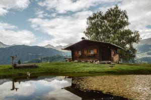 ein kleines Holzhaus auf einem Hügel mit einem Teich in der Unterkunft Weiherhütte Ried in Ried im Oberinntal