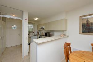 a kitchen with white cabinets and a table in it at Rustig gelegen vakantiehuisje met zwembad op wandelafstand van zeedijk en jachthaven. in Nieuwpoort