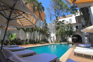 einen Pool mit Stühlen und Sonnenschirmen neben einem Gebäude in der Unterkunft Casa Pestagua Relais Châteaux in Cartagena de Indias