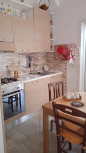 a kitchen with white cabinets and a table and a table and chairs at Casa Sofia: comodi e tranquilli in Maruggio