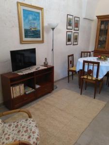 a living room with a tv and a table and chairs at Casa Sofia: comodi e tranquilli in Maruggio