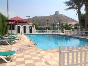 einem Pool mit Stühlen und einem Berg im Hintergrund in der Unterkunft Hotel Iberico in Castell de Ferro