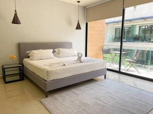 a bedroom with a bed and a large window at 2BR Modern 5th Avenue Apt -Distrito Corazon D1 in Playa del Carmen