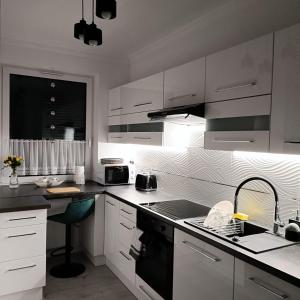 a kitchen with white cabinets and a black stove top oven at BELWEDER in Nysa