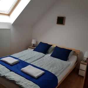 Schlafzimmer mit einem Bett mit blauer Bettwäsche und Kissen in der Unterkunft Osada nad Potokiem in Szczyrk