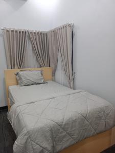 uma cama com um edredão cinzento num quarto em Anyak's place Syariah em Yogyakarta