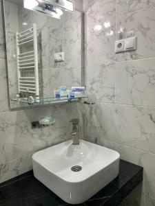 a white bathroom with a sink and a mirror at Duplex apartment near the forest in Bakuriani