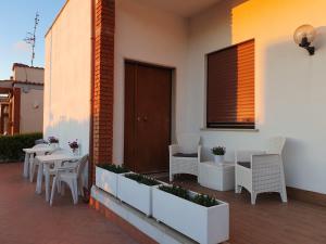 eine Terrasse mit weißen Stühlen, Tischen und einem Fenster in der Unterkunft Guest house al mare in Civitavecchia
