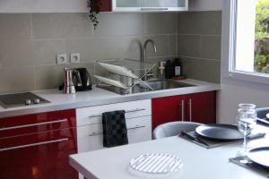 uma cozinha com armários vermelhos, um lavatório e uma mesa em Red Lounge em Toulouse