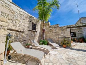 a group of chairs and a palm tree on a patio at Poseidon's Pool Paradise in Skarinou
