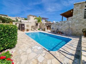 a swimming pool in a yard with a stone house at Poseidon's Pool Paradise in Skarinou