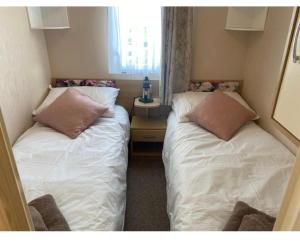 2 letti in una piccola camera con finestra di Home by the sea, Hoburne Naish Resort, sleeps 4, on site leisure complex available a Milford on Sea