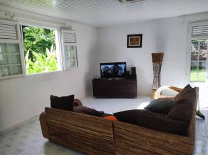 een woonkamer met een bank en 2 ramen bij Villa familiale avec piscine in Le Marin