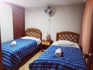 1 dormitorio con 2 camas y toallas. en Hostal Turístico El Cajamarquez, en Lima