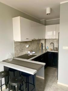 a kitchen with white cabinets and a counter with stools at Apartament Poznańska 24 in Bydgoszcz
