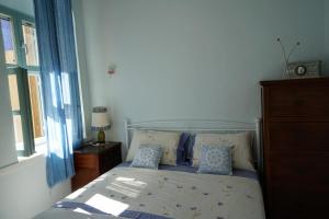 a bedroom with a bed with blue curtains and a window at Say Yes Symi House in Symi