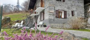 a house with two chairs and purple flowers in front of it at Baita salzkabe in Macugnaga