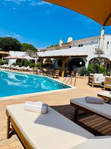 une piscine avec une table et des chaises et un bâtiment dans l'établissement Hôtel Palombaggia, Certifié Ecolabel Européen, à Porto-Vecchio