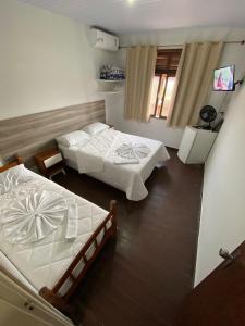 um quarto com duas camas e uma televisão em Hotel Montanus em Nova Friburgo