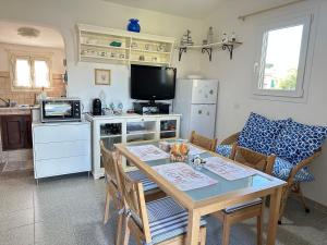 ein Wohnzimmer mit einem Tisch und eine Küche mit einem TV in der Unterkunft CASA IL PINO in Orbetello
