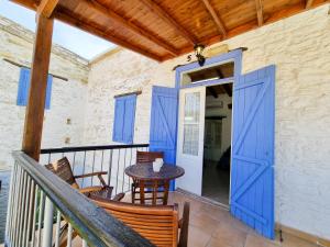 a porch with blue doors and a table and chairs at Poseidon's Pool Paradise in Skarinou