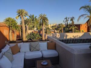 un patio con sofá, palmeras y mesa en Riad Rossi en Marrakech