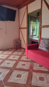 salon z czerwoną kanapą i telewizorem w obiekcie FINCA HOTEL LA DORADA EJE CAFETERO w mieście Puerto Espejo