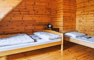 two beds in a room with wooden walls at Chłopy Domki u Jacola in Chłopy