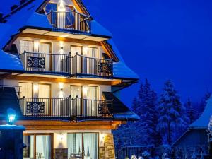 ein Gebäude mit Balkon in der Nacht mit Schnee in der Unterkunft Villa Taternik by Golden Villas in Zakopane